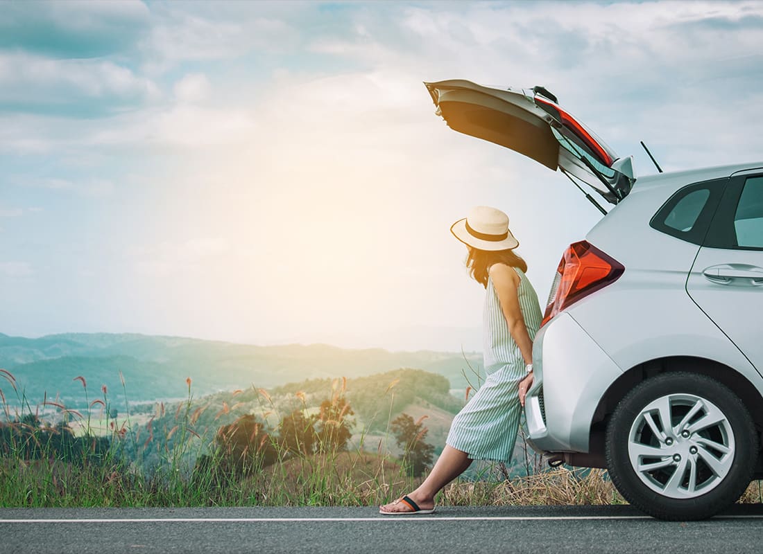 Auto Insurance - Woman Traveler Sitting on Hatchback Car With Mountain Background in Vintage Tone