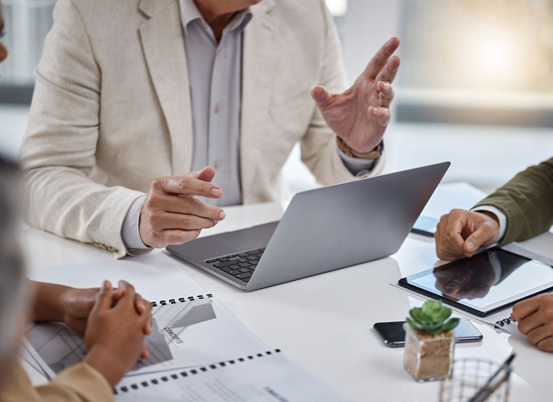 Bonds - Group Gather Around a Table With Papers and Laptops and Tablets on Top