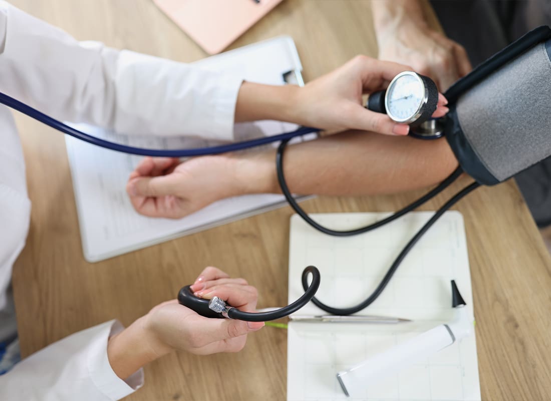 Employee Benefits - Female Doctor Using Sphygmomanometer Checks Patient’s Blood Pressure in Medical Clinic