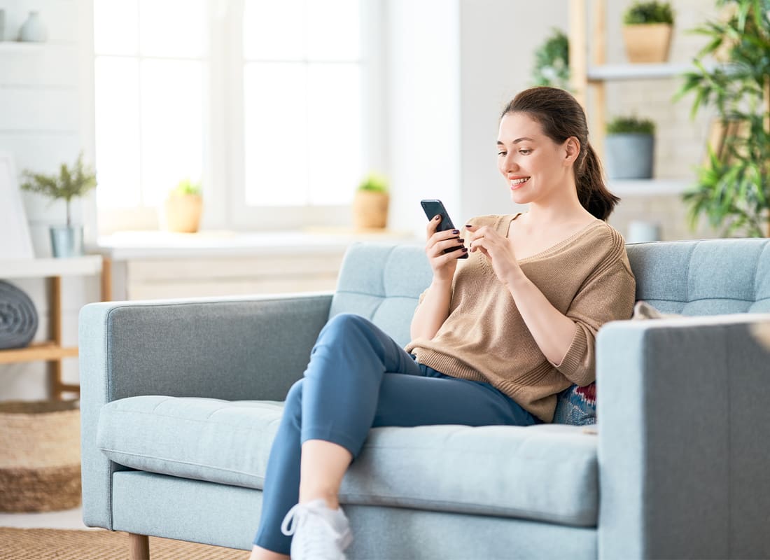 Read Our Reviews - Woman Looking at Her Phone From Her Couch at Home